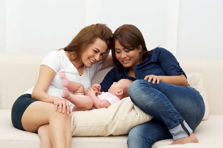 Two women on a couch with their baby. same-sex