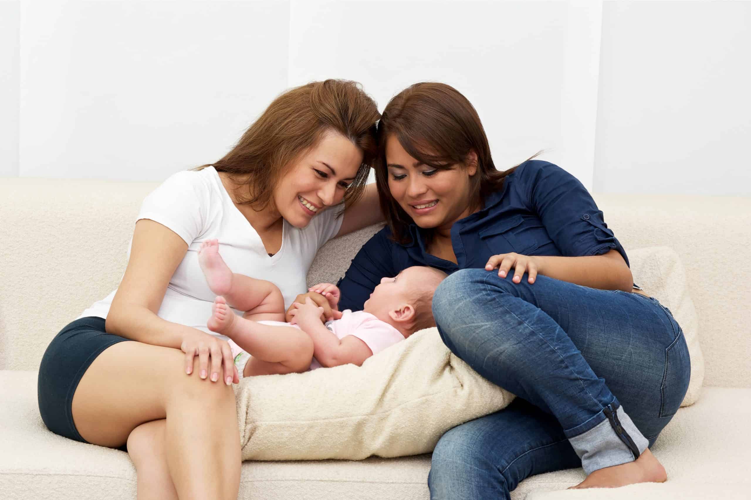 Two women on a couch with their baby. same-sex