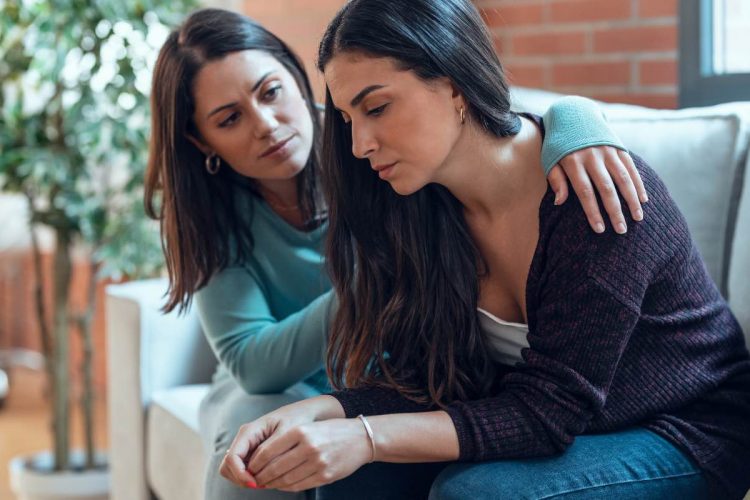 Two women comforting each other on a couch