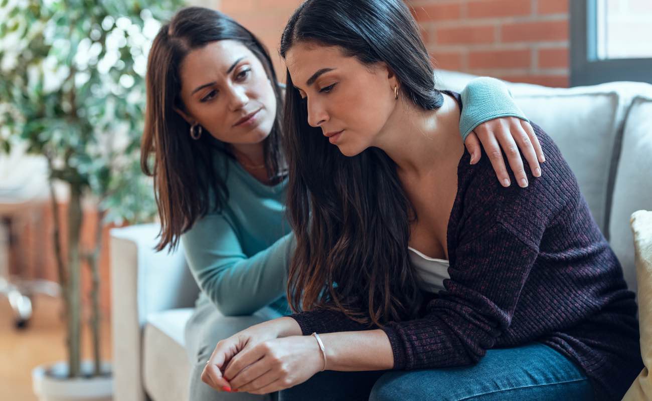 Two women comforting each other on a couch