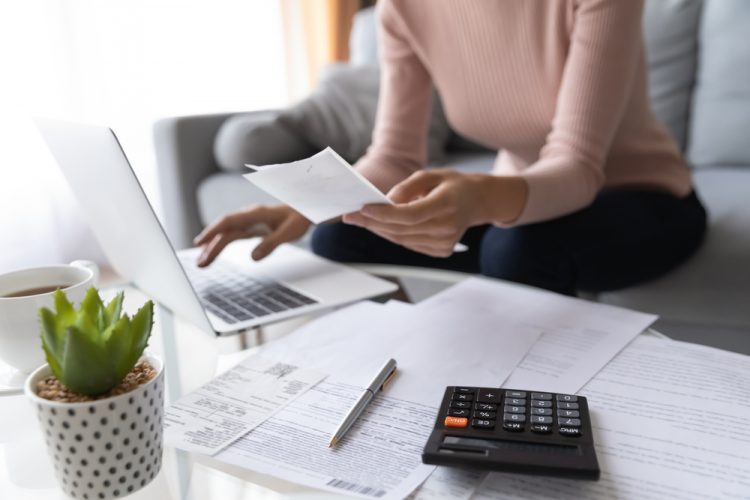 A woman works out finances at her computer.